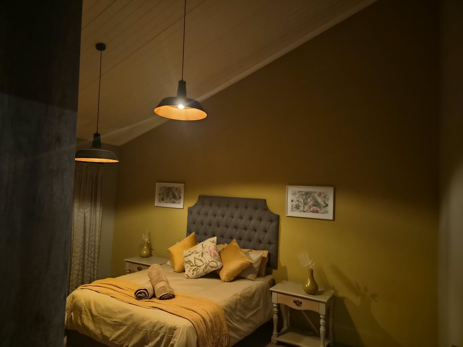 Earthy green bedroom with warm pendant lighting